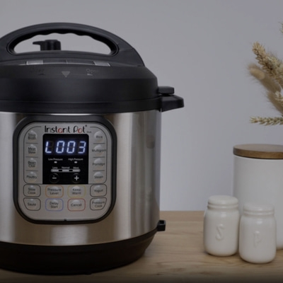 Instant Pot mit Anzeige L003, daneben Salzstreuer und ein Behälter auf Holz