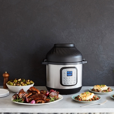 Instant Pot mit Essen, Gemüse und Tellern auf einem Tisch
