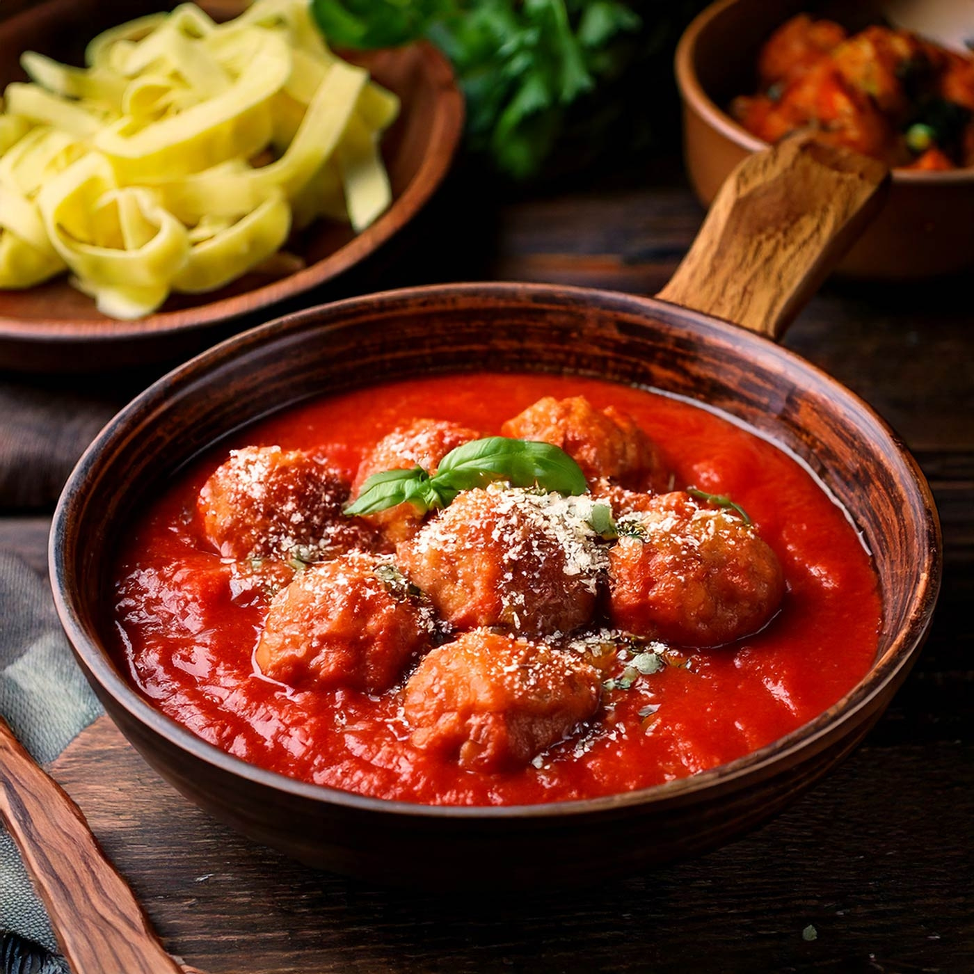 Fleischbällchen in Tomatensauce mit Pasta und Basilikum, rustikal serviert