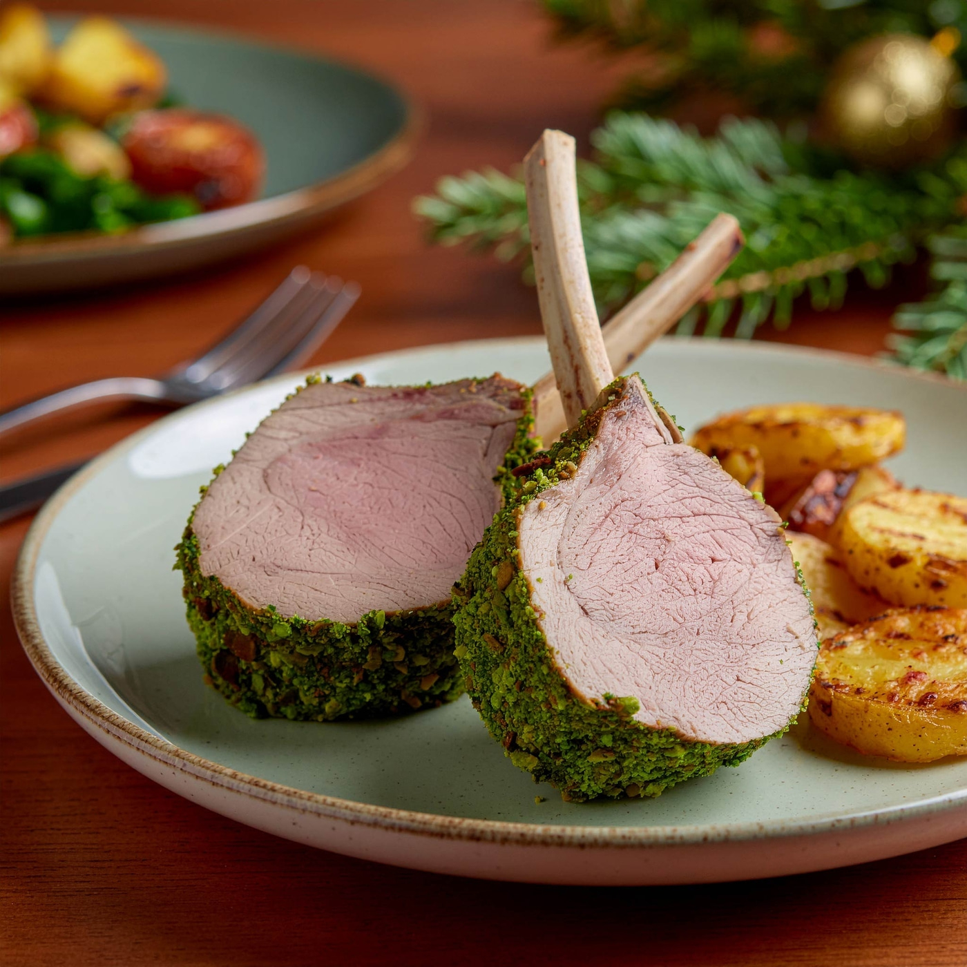 Gebratenes Lammkotelett mit Pistazienkruste und Bratkartoffeln auf einem Teller