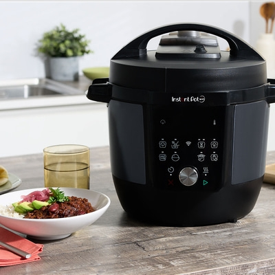 Schwarzer Instant Pot mit Essen auf einem Holztisch in der Küche.