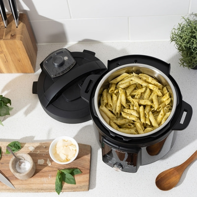 Instant Pot mit Pasta, Zutaten auf Holzbrett, Kochutensilien, Nahaufnahme