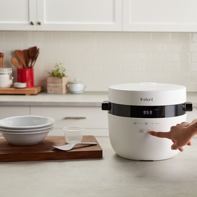 Instant-Kocher mit Hand, Schüsseln und Zubehör auf einer Küchenarbeitsplatte