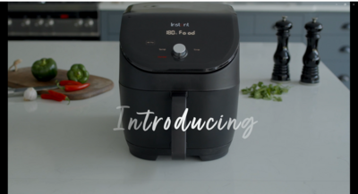 Schwarze Heißluftfritteuse mit Gemüse auf einer Küchenarbeitsplatte. Einführung.