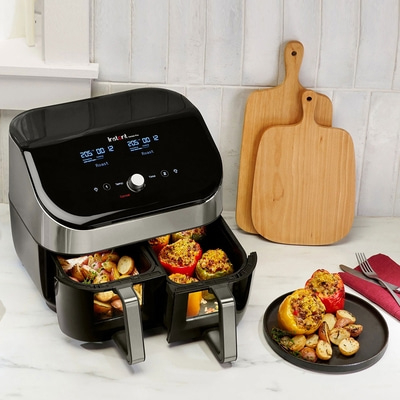 Instant Vortex Plus Heißluftfritteuse mit Gemüse und Schneidebrettern auf dem Tisch