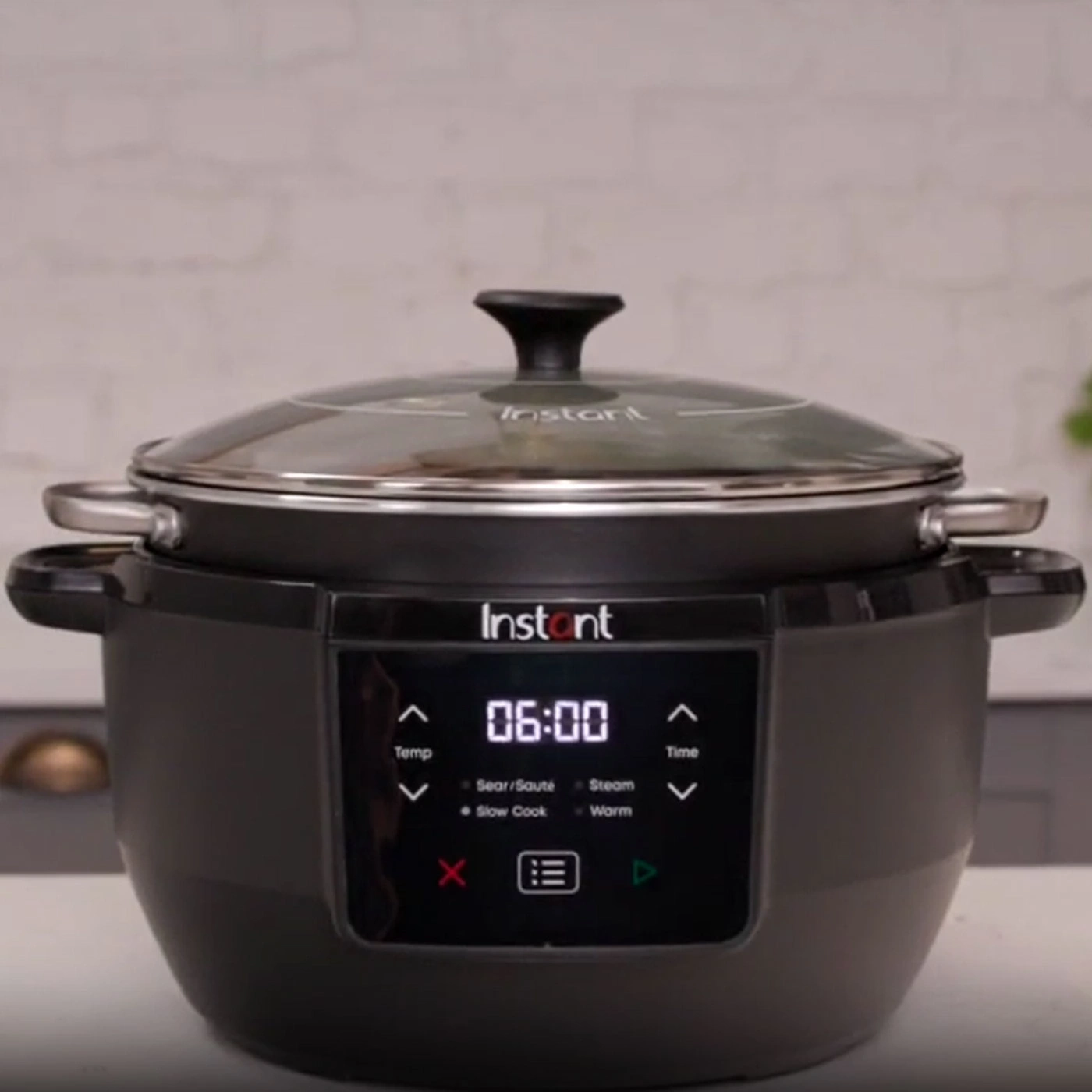 Ein schwarzer Instant Pot mit Glasdeckel und digitaler Anzeige, die 06:00 zeigt.
