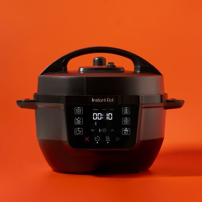 Schwarzer Instant Pot auf orangefarbenem Hintergrund, Kochfeld mit Anzeige