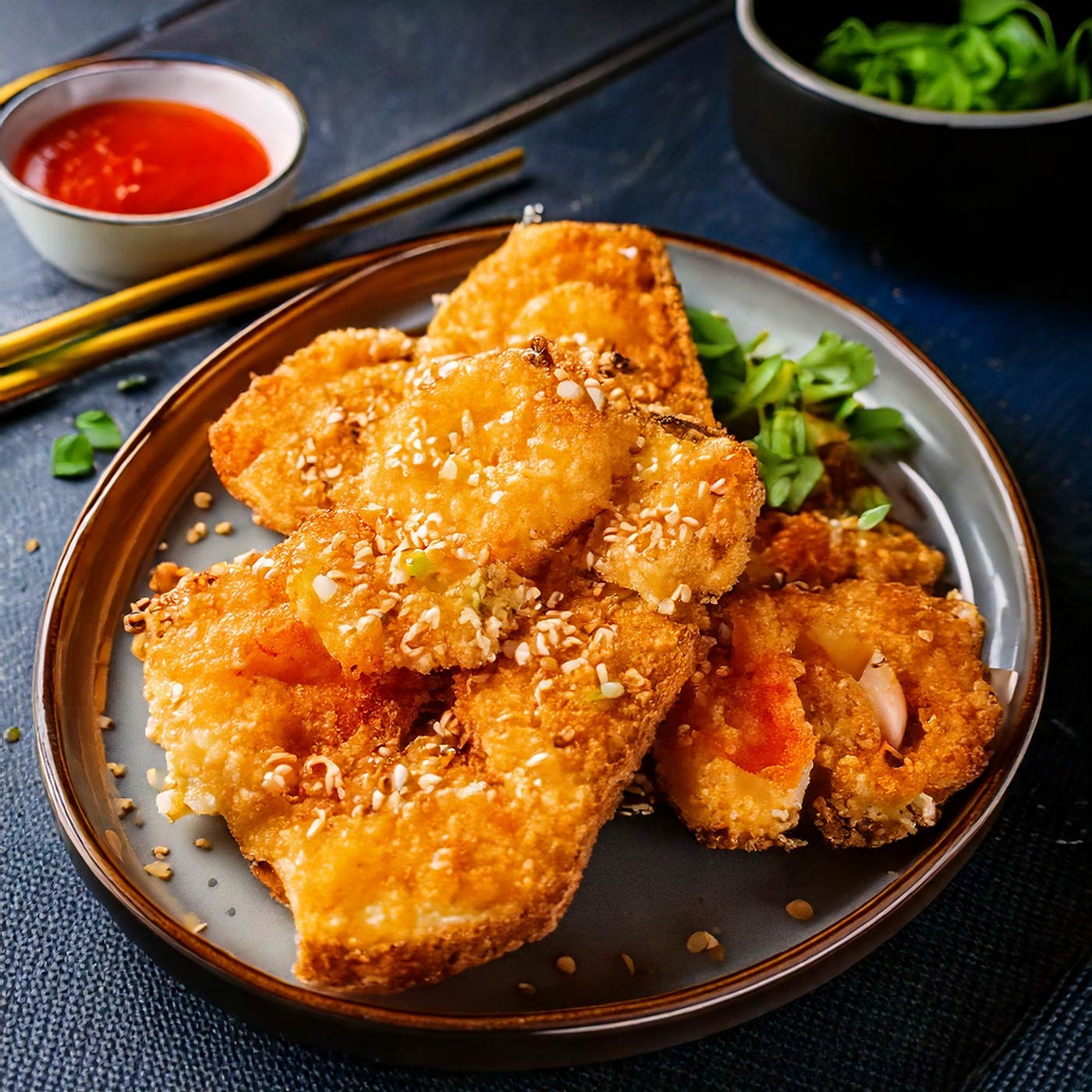 Gebratene Speisen mit Sesam, Soße und Stäbchen auf einem Teller